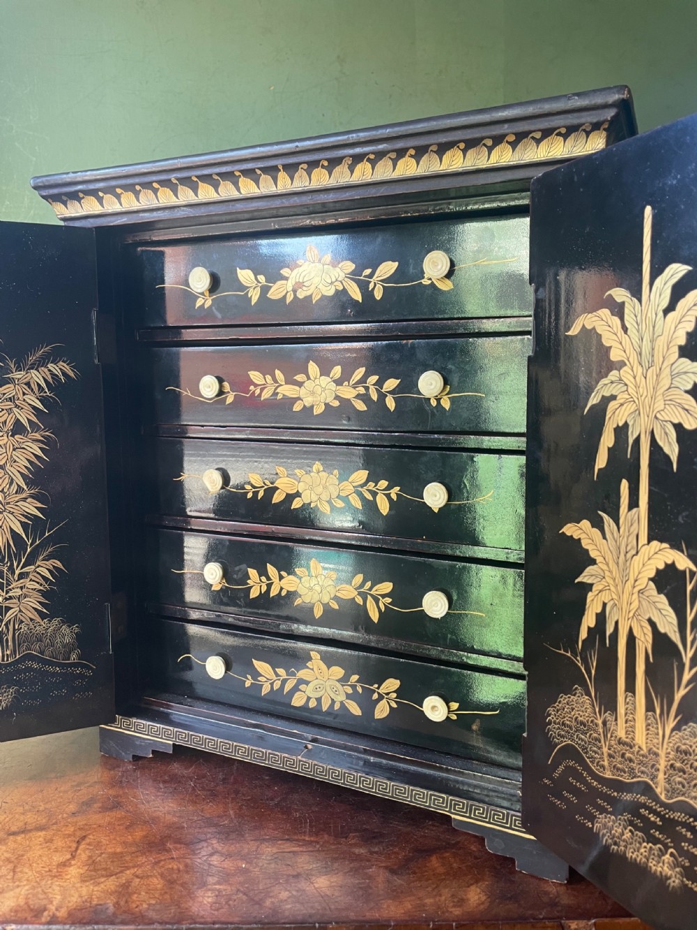 A mid-nineteenth century Chinese export black lacquer table cabinet featuring two doors decorated with gilded figural landscapes, floral borders, and geometric motifs. View XVIII