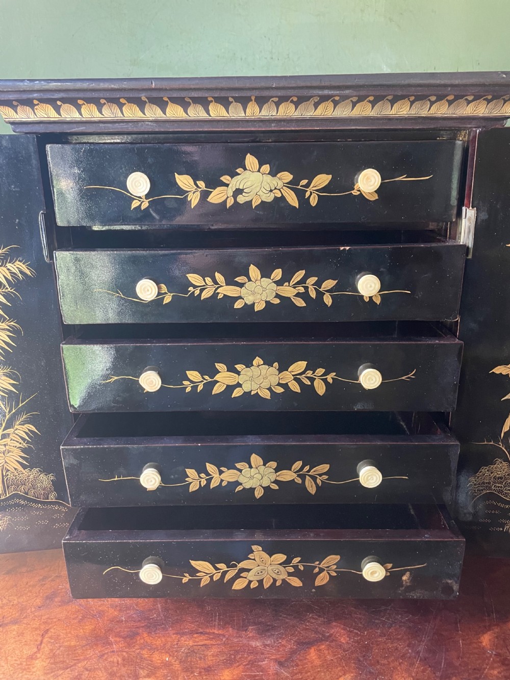 A mid-nineteenth century Chinese export black lacquer table cabinet featuring two doors decorated with gilded figural landscapes, floral borders, and geometric motifs. View XIX