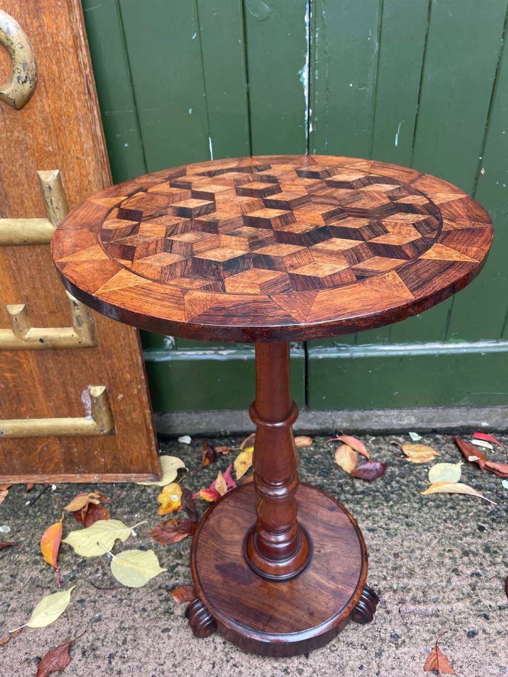 A 19th-century William IV circular occasional table featuring a geometric optical parquetry top set on a turned column stem and plinth base.