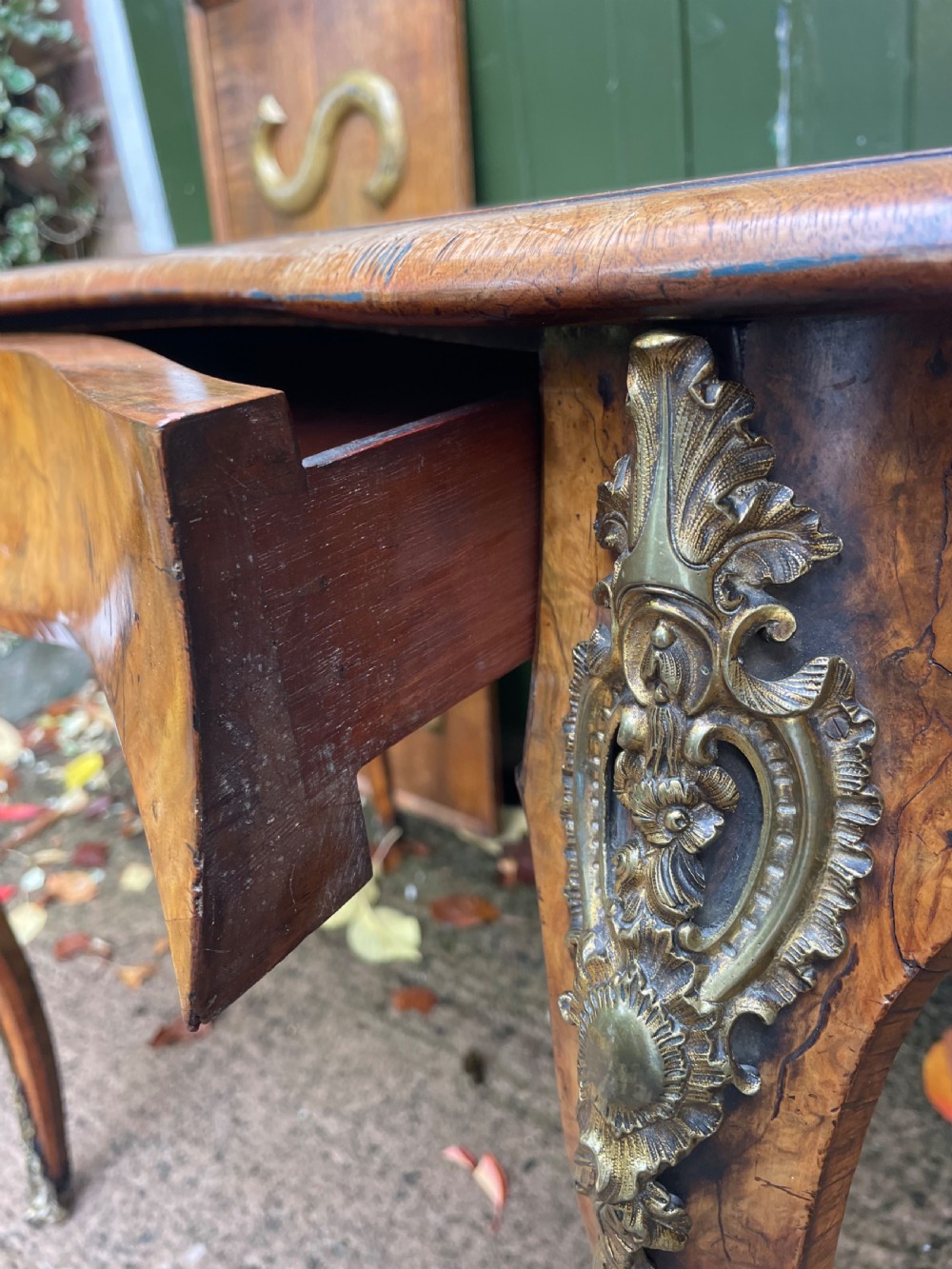 A mid-19th-century kidney-shaped burr walnut writing table with an inset leather surface and cast ormolu mounts on cabriole legs. View XVII