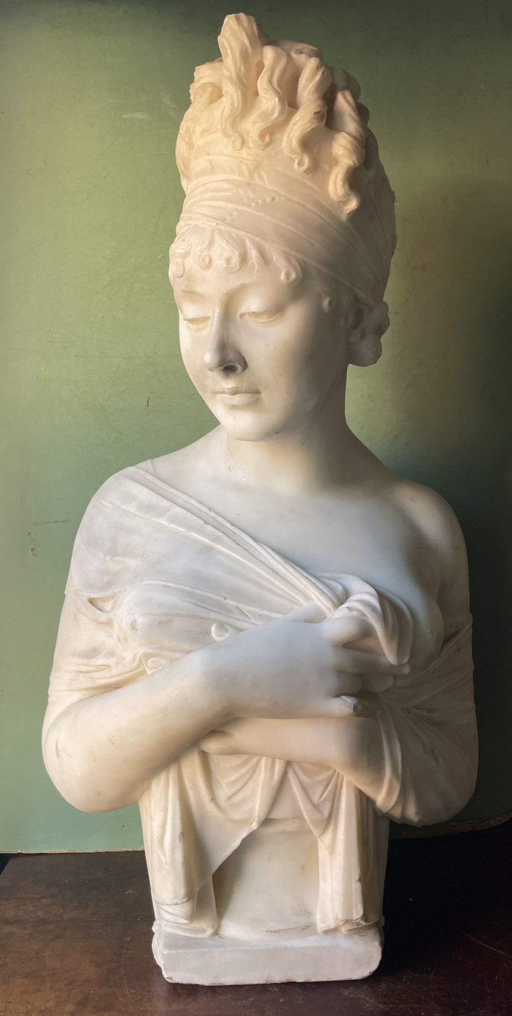 A late nineteenth-century carved white statuary marble portrait bust depicting a female figure with draped cloth held across her chest and stylized hair.