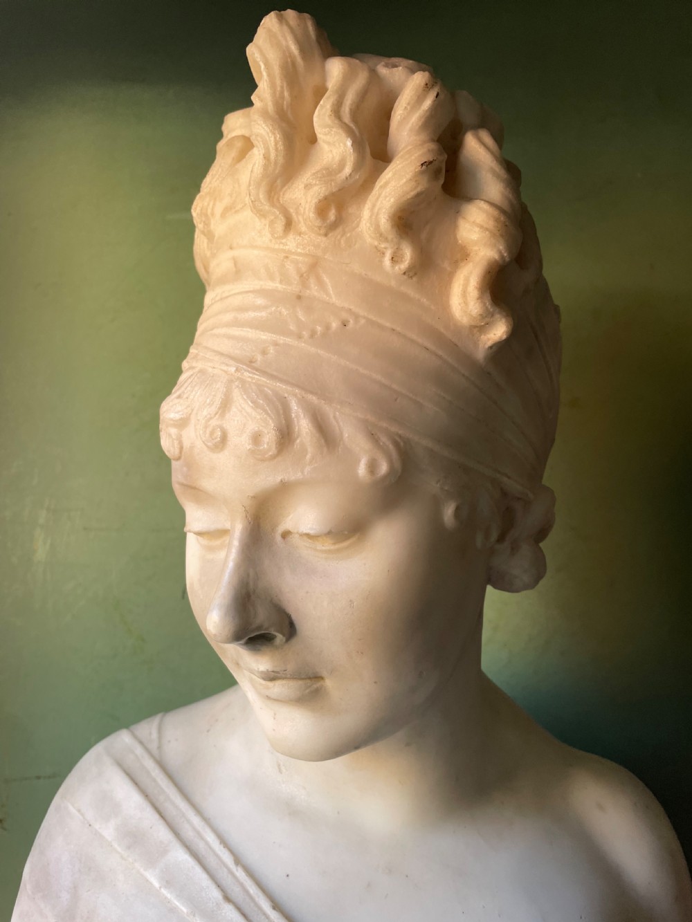 A late nineteenth-century carved white statuary marble portrait bust depicting a female figure with draped cloth held across her chest and stylized hair. View IV