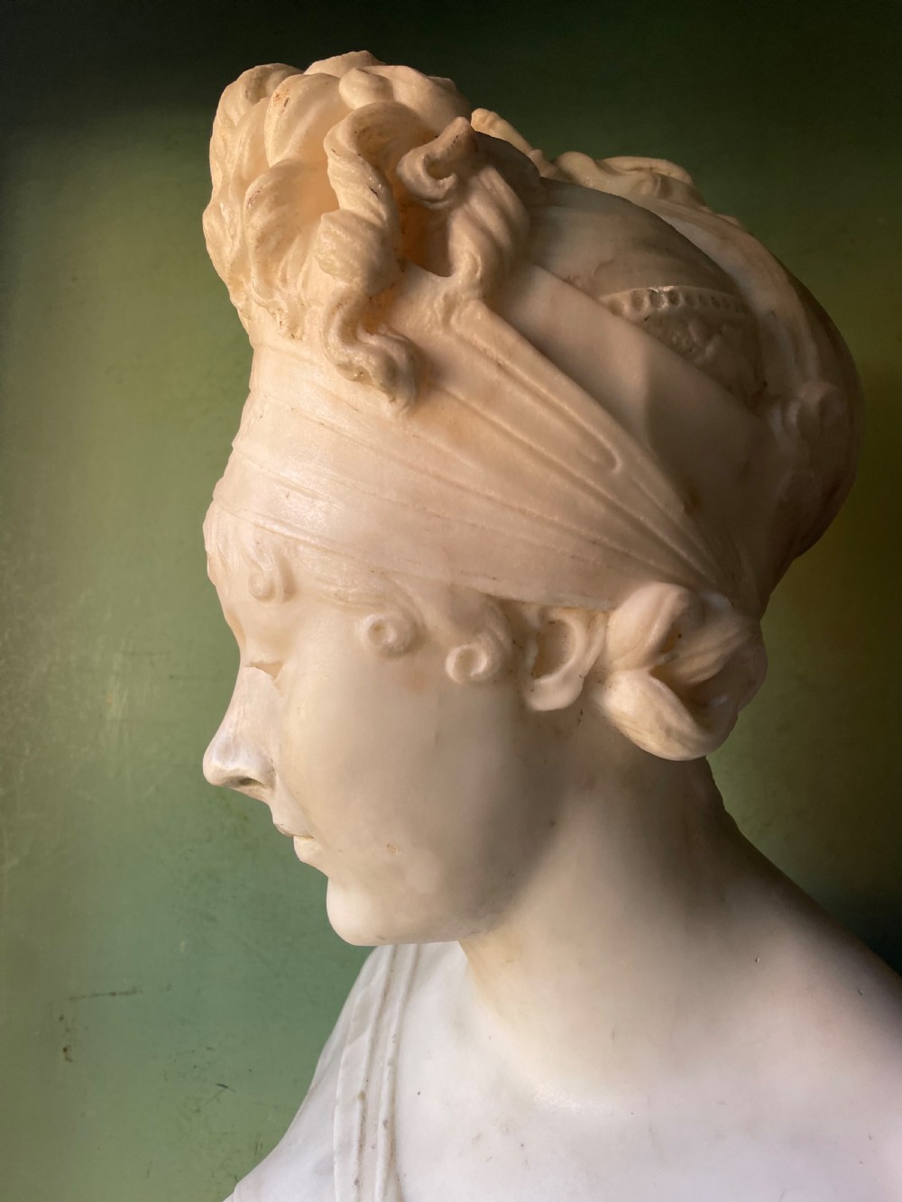 A late nineteenth-century carved white statuary marble portrait bust depicting a female figure with draped cloth held across her chest and stylized hair. View V