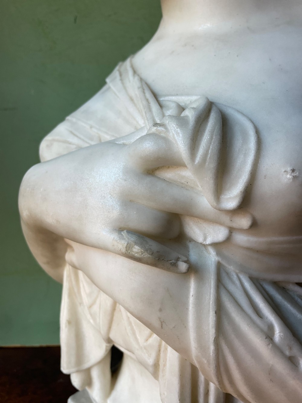 A late nineteenth-century carved white statuary marble portrait bust depicting a female figure with draped cloth held across her chest and stylized hair. View VI