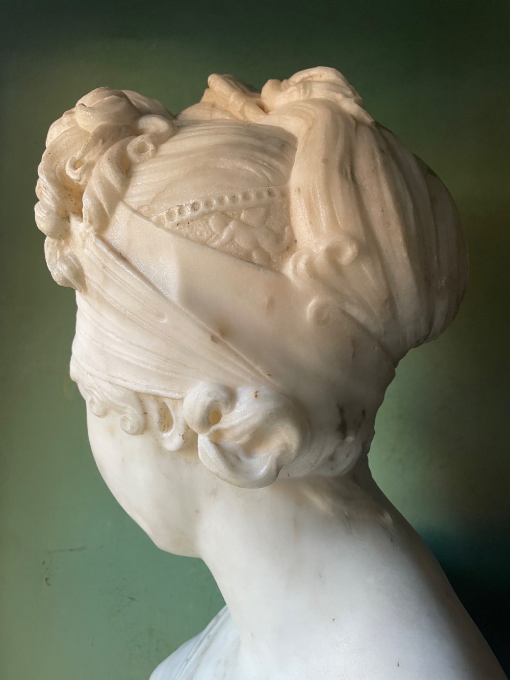 A late nineteenth-century carved white statuary marble portrait bust depicting a female figure with draped cloth held across her chest and stylized hair. View VII