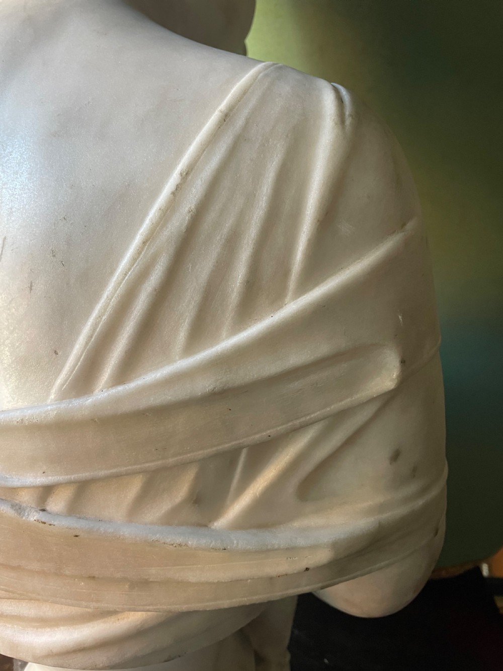 A late nineteenth-century carved white statuary marble portrait bust depicting a female figure with draped cloth held across her chest and stylized hair. View X
