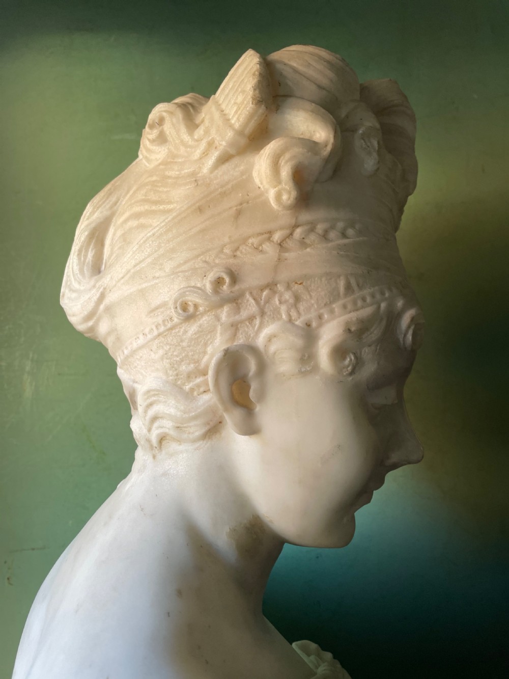 A late nineteenth-century carved white statuary marble portrait bust depicting a female figure with draped cloth held across her chest and stylized hair. View XI
