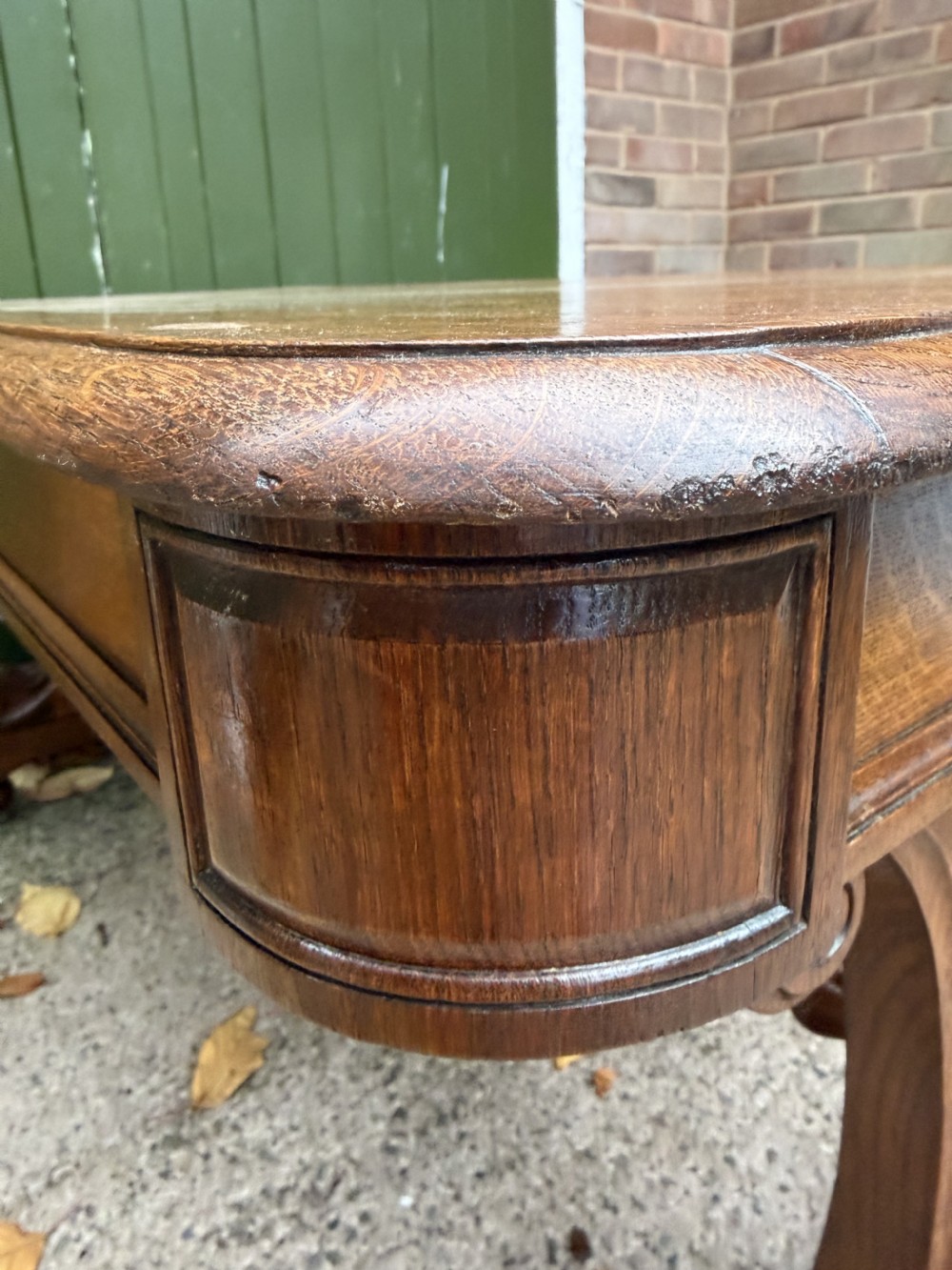 An early 19th-century William IV oak library table featuring a central carved acorn frieze panel, scrolled trestle supports, and a turned stretcher base. View XII