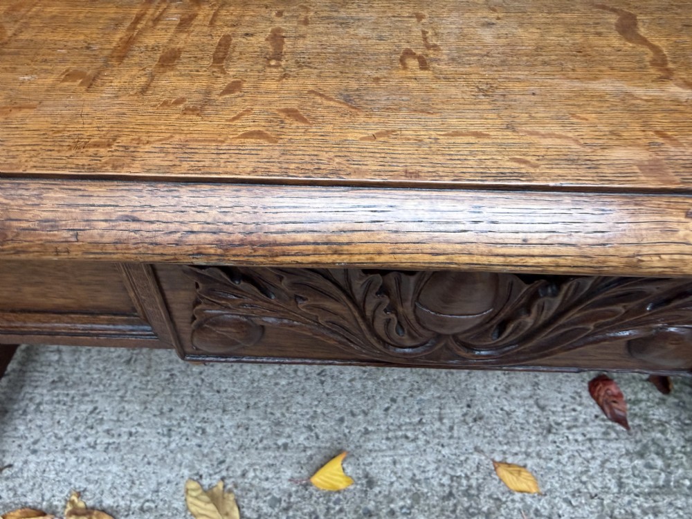 An early 19th-century William IV oak library table featuring a central carved acorn frieze panel, scrolled trestle supports, and a turned stretcher base. View XXIII