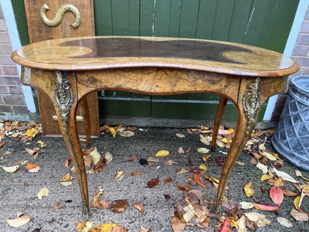 A mid-19th-century kidney-shaped burr walnut writing table with an inset leather surface and cast ormolu mounts on cabriole legs. View III