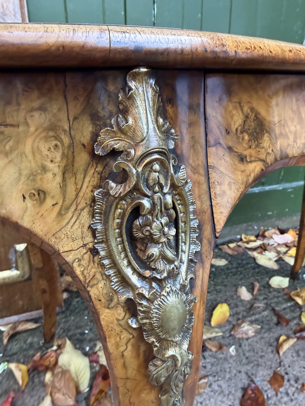 A mid-19th-century kidney-shaped burr walnut writing table with an inset leather surface and cast ormolu mounts on cabriole legs. View IV
