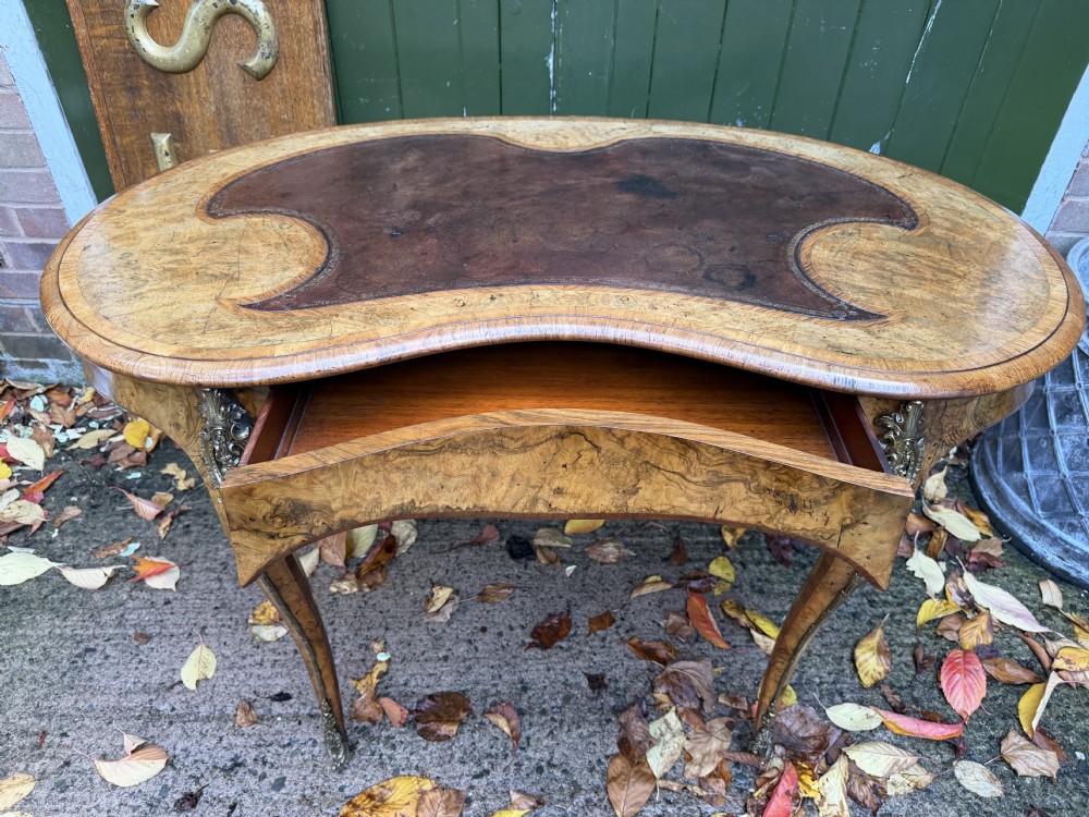 A mid-19th-century kidney-shaped burr walnut writing table with an inset leather surface and cast ormolu mounts on cabriole legs. View VIII