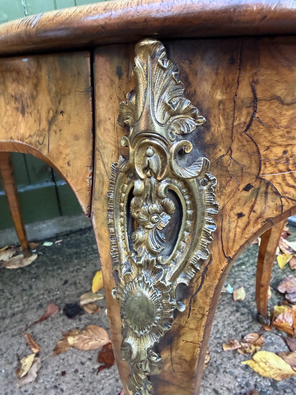 A mid-19th-century kidney-shaped burr walnut writing table with an inset leather surface and cast ormolu mounts on cabriole legs. View XVIII