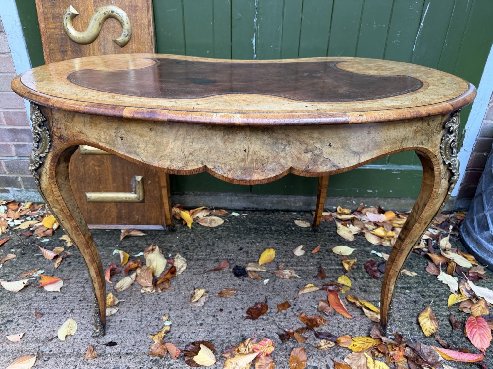 A mid-19th-century kidney-shaped burr walnut writing table with an inset leather surface and cast ormolu mounts on cabriole legs. View XIX