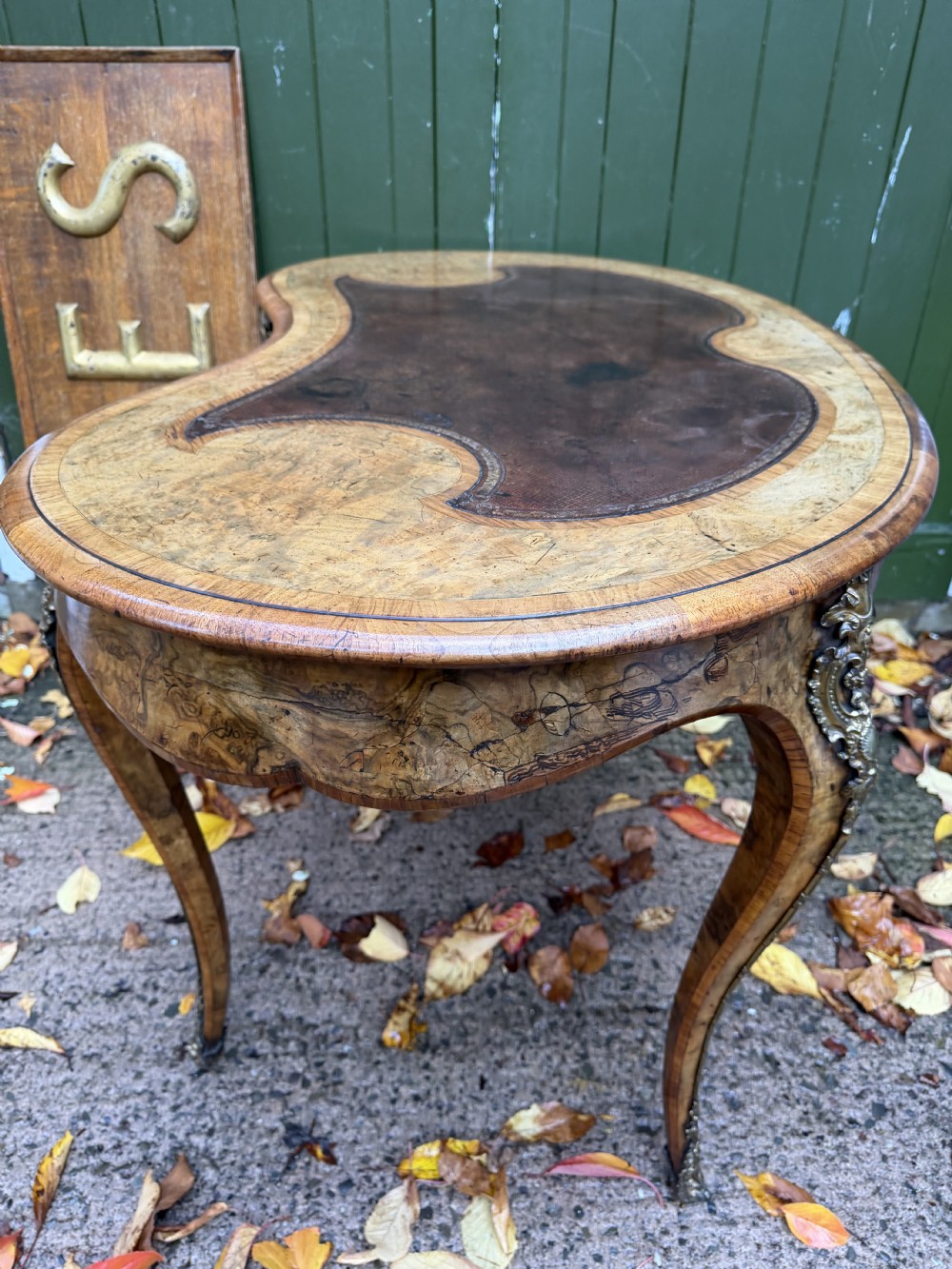 A mid-19th-century kidney-shaped burr walnut writing table with an inset leather surface and cast ormolu mounts on cabriole legs. View XXI