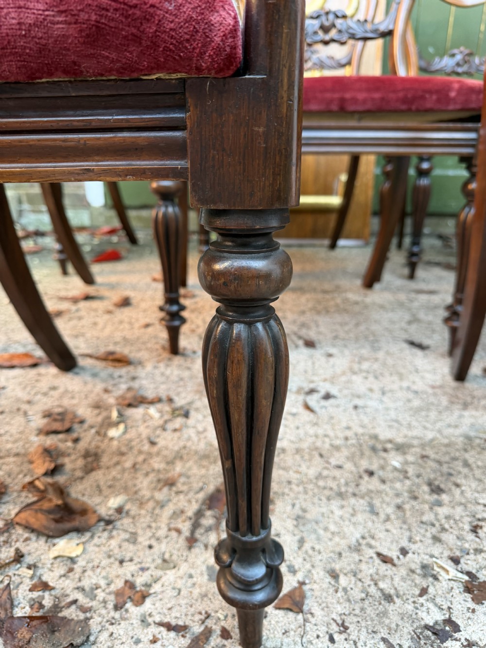 A set of eight early 19th-century William IV rosewood dining chairs with carved back rails, fluted front legs, and red velvet seats. View IX