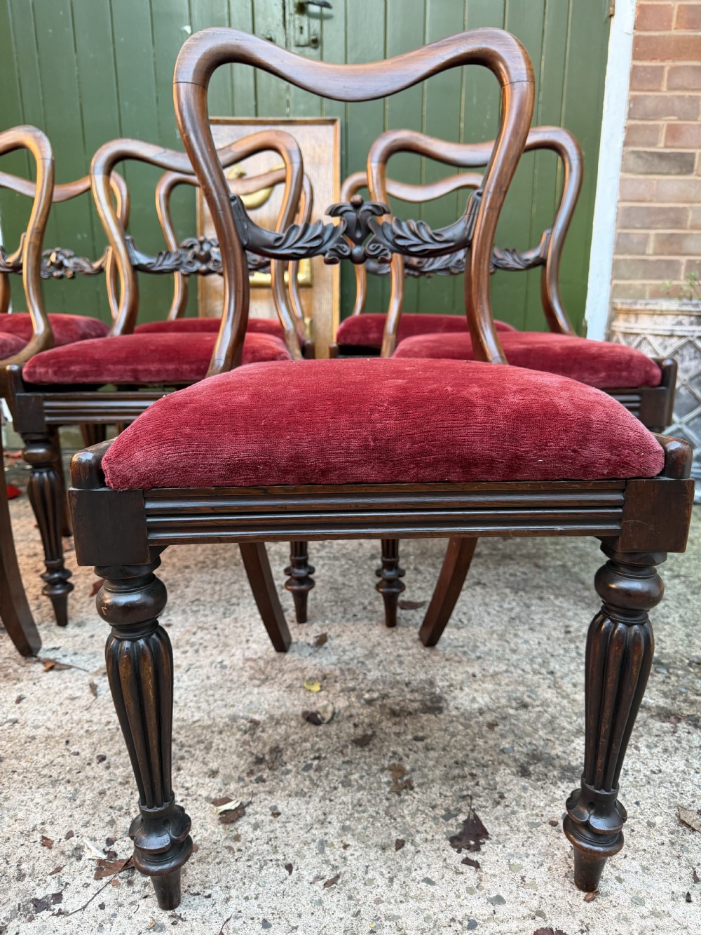 A set of eight early 19th-century William IV rosewood dining chairs with carved back rails, fluted front legs, and red velvet seats. View X