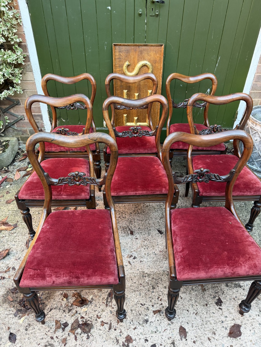 A set of eight early 19th-century William IV rosewood dining chairs with carved back rails, fluted front legs, and red velvet seats. View XX