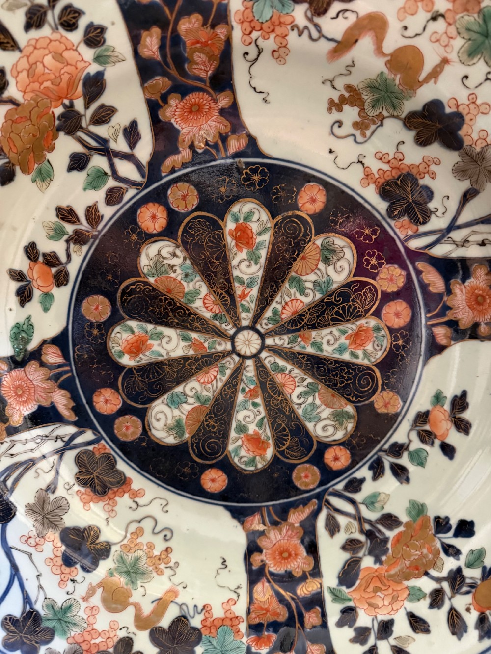 A circular Japanese Imari porcelain dished charger decorated in cobalt blue, iron-red, green, and gold with central chrysanthemum and floral panel designs. View III