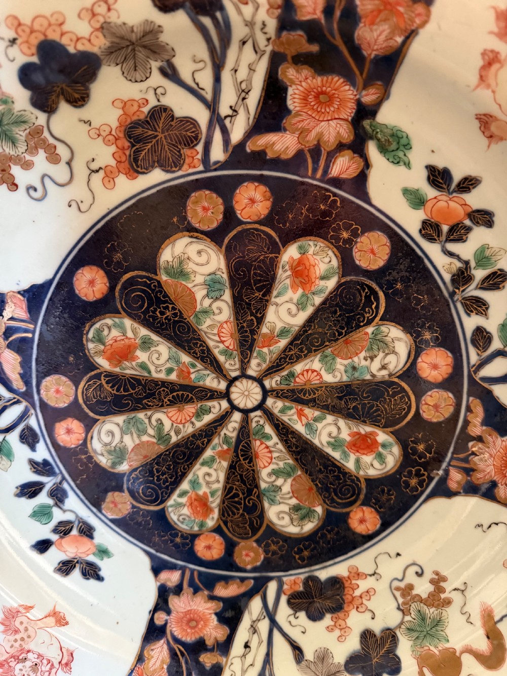 A circular Japanese Imari porcelain dished charger decorated in cobalt blue, iron-red, green, and gold with central chrysanthemum and floral panel designs. View XI