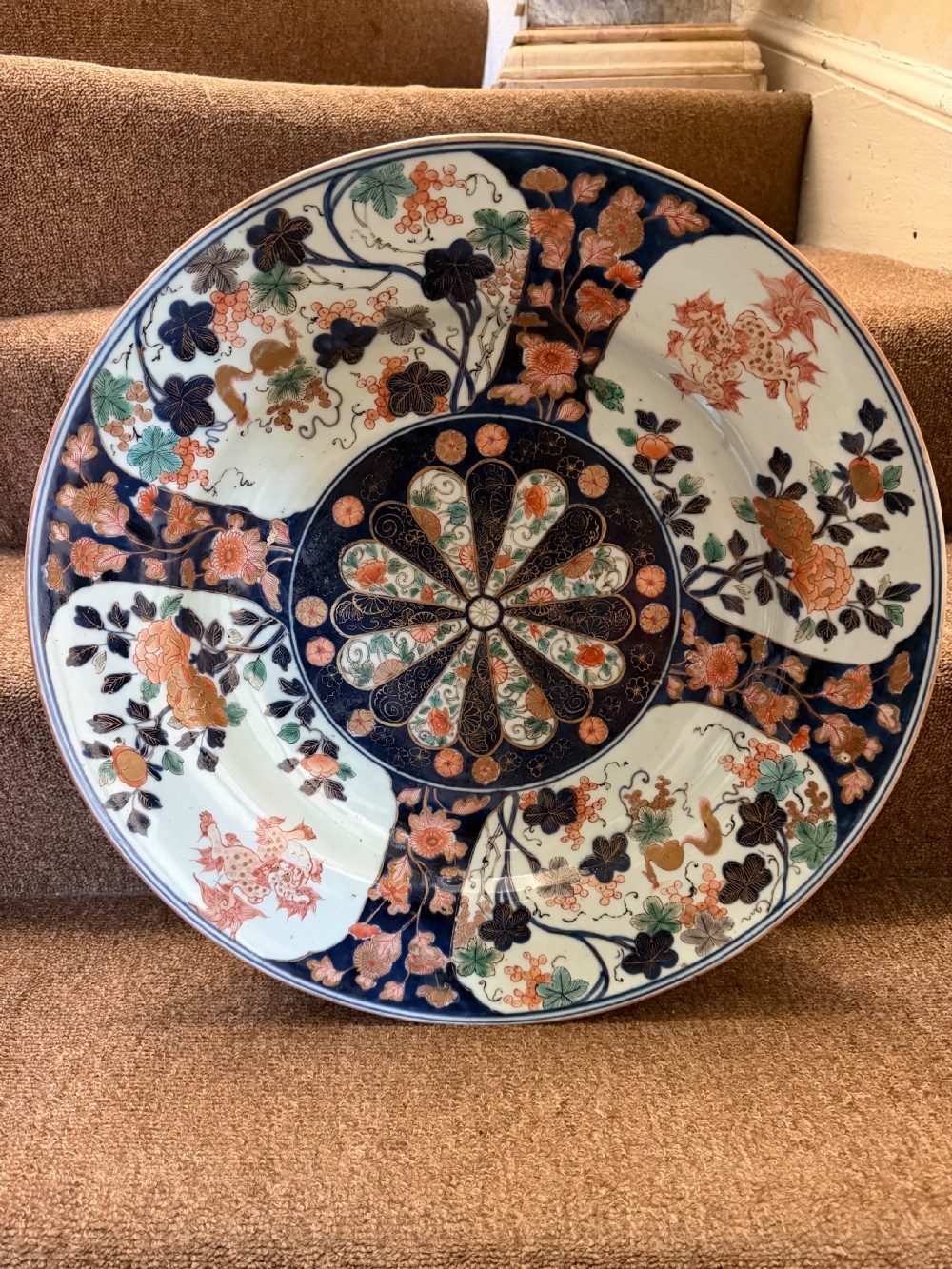 A circular Japanese Imari porcelain dished charger decorated in cobalt blue, iron-red, green, and gold with central chrysanthemum and floral panel designs. View XII