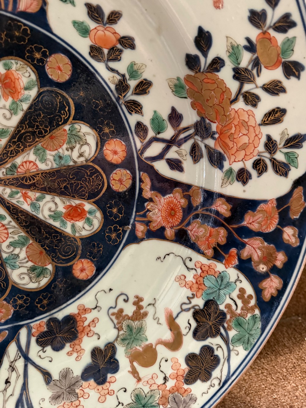 A circular Japanese Imari porcelain dished charger decorated in cobalt blue, iron-red, green, and gold with central chrysanthemum and floral panel designs. View XIII