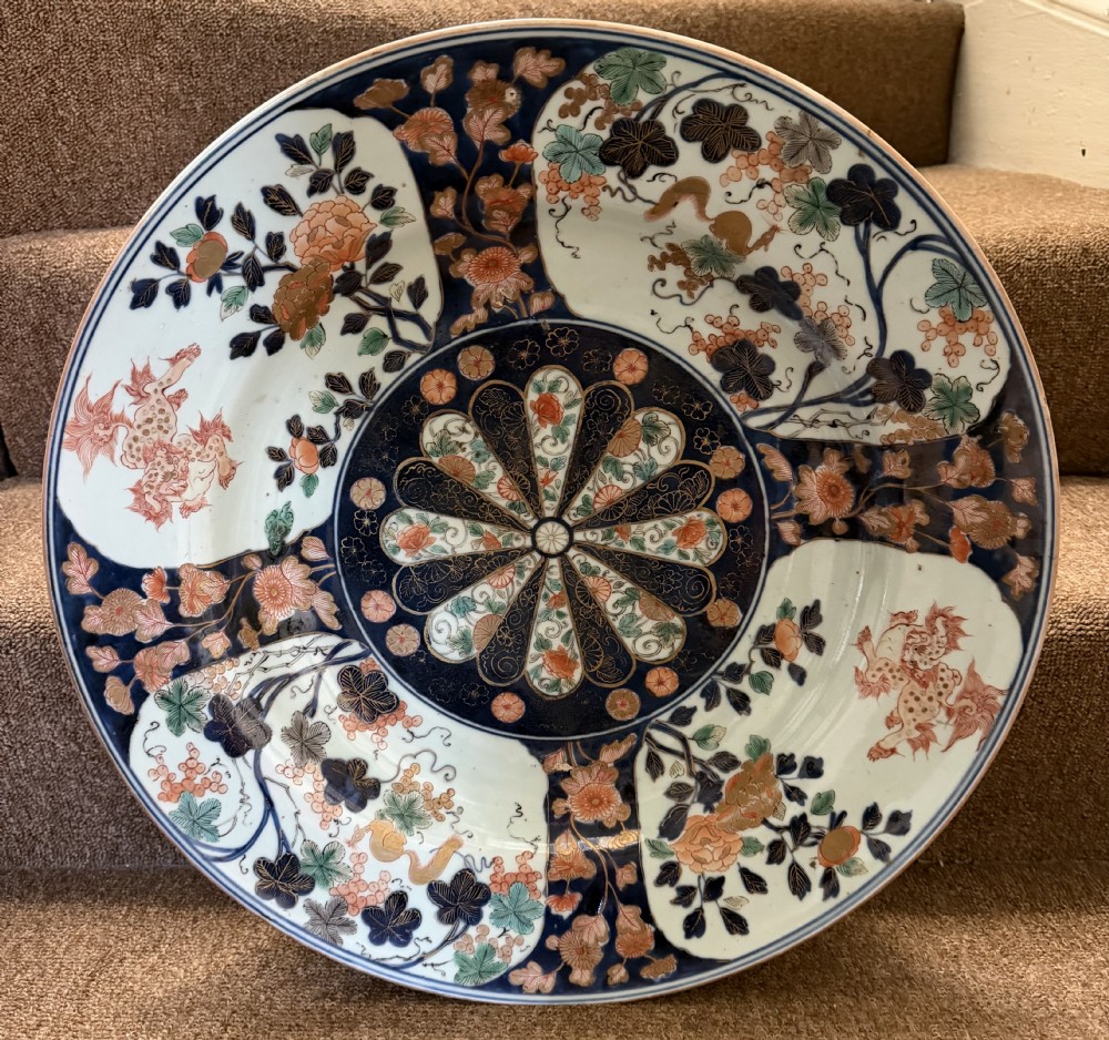 A circular Japanese Imari porcelain dished charger decorated in cobalt blue, iron-red, green, and gold with central chrysanthemum and floral panel designs. View II