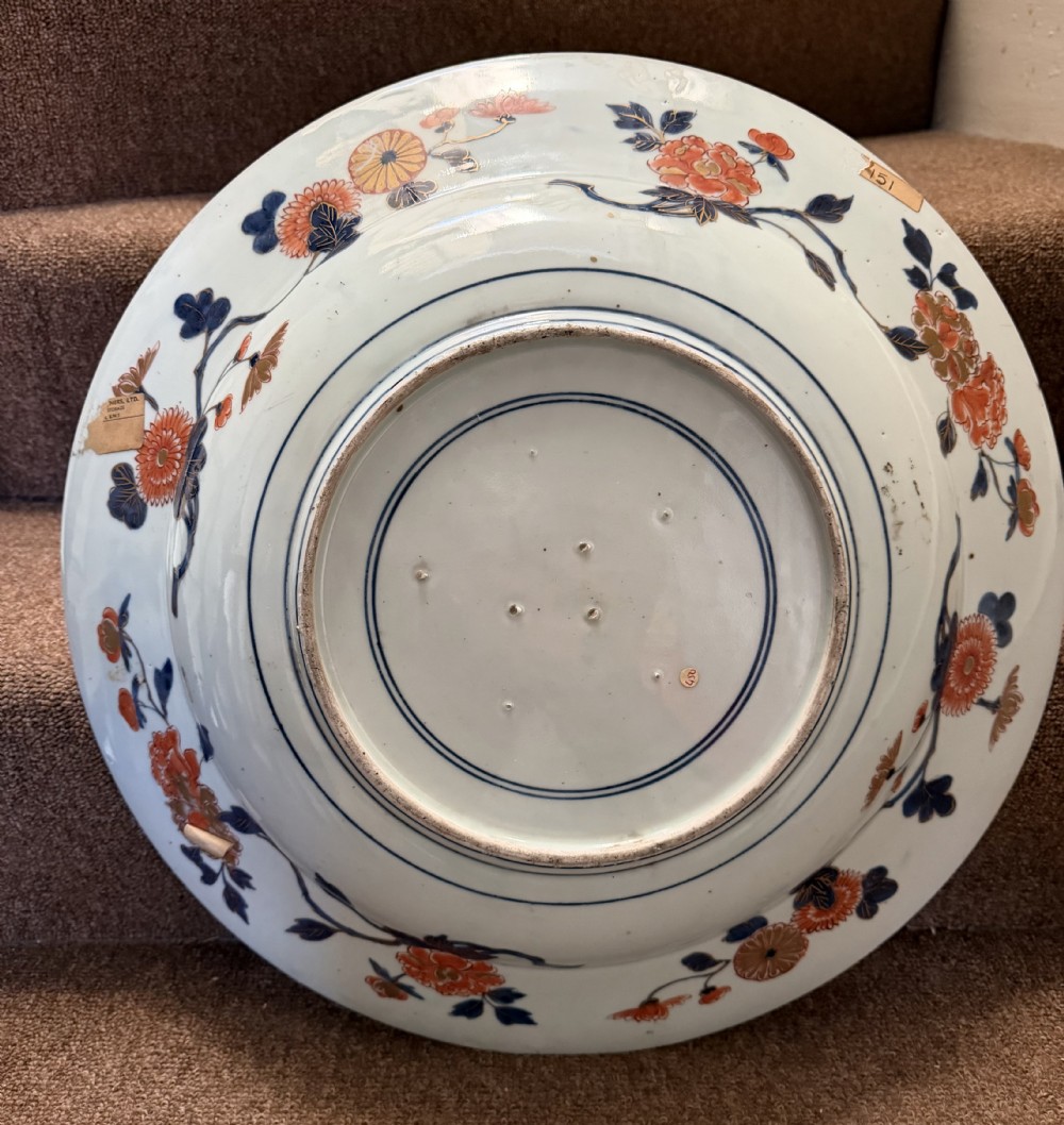 A circular Japanese Imari porcelain dished charger decorated in cobalt blue, iron-red, green, and gold with central chrysanthemum and floral panel designs. View XIV