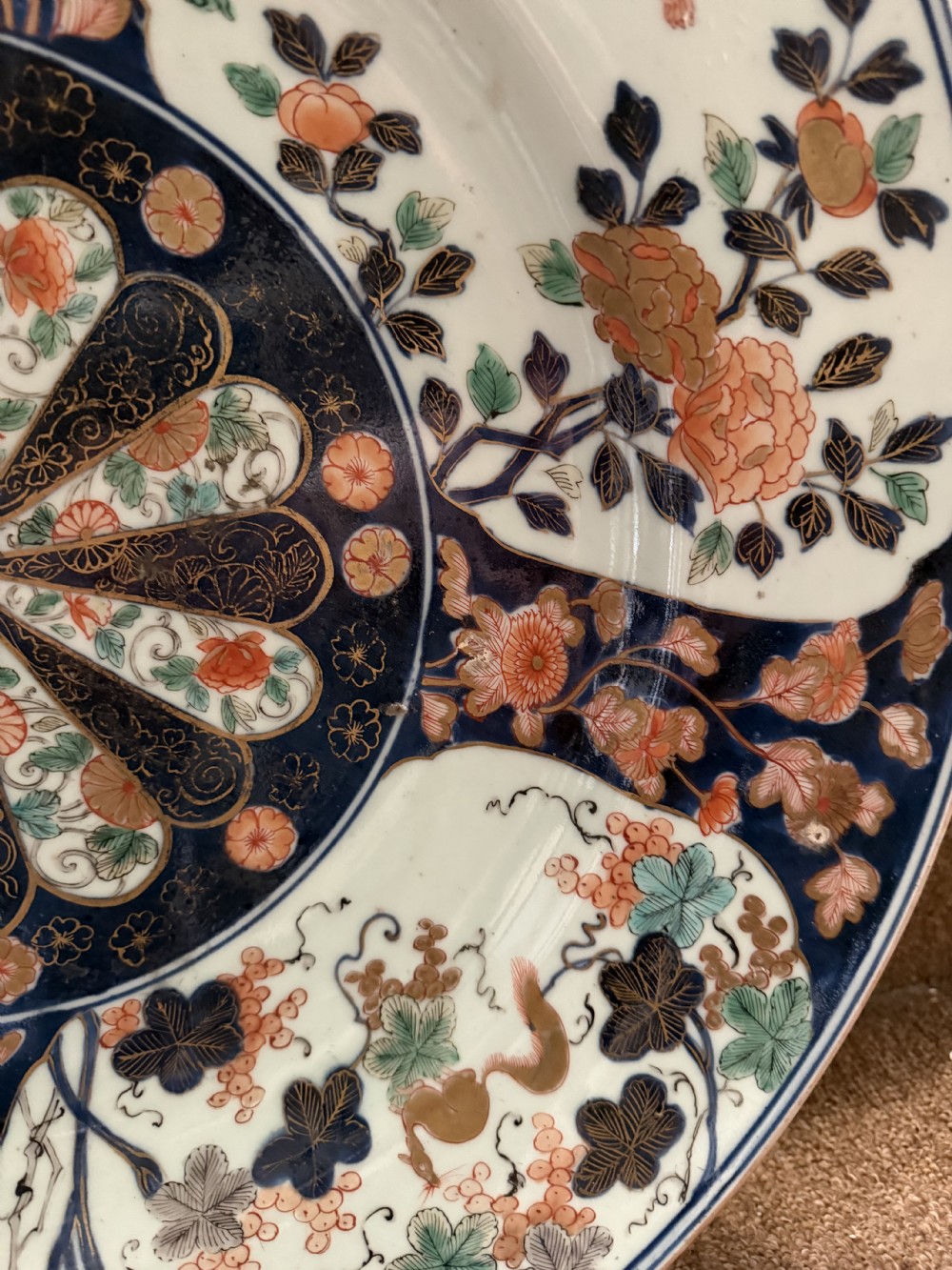 A circular Japanese Imari porcelain dished charger decorated in cobalt blue, iron-red, green, and gold with central chrysanthemum and floral panel designs. View XVI