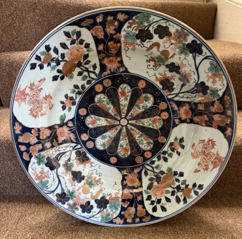 A circular Japanese Imari porcelain dished charger decorated in cobalt blue, iron-red, green, and gold with central chrysanthemum and floral panel designs. View XVII