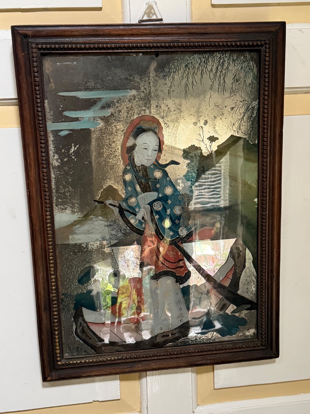 An early nineteenth-century Chinese export reverse glass picture featuring a figure on a boat against a silvered mirror background, encased in a dark wooden frame with beaded inner moulding. View II