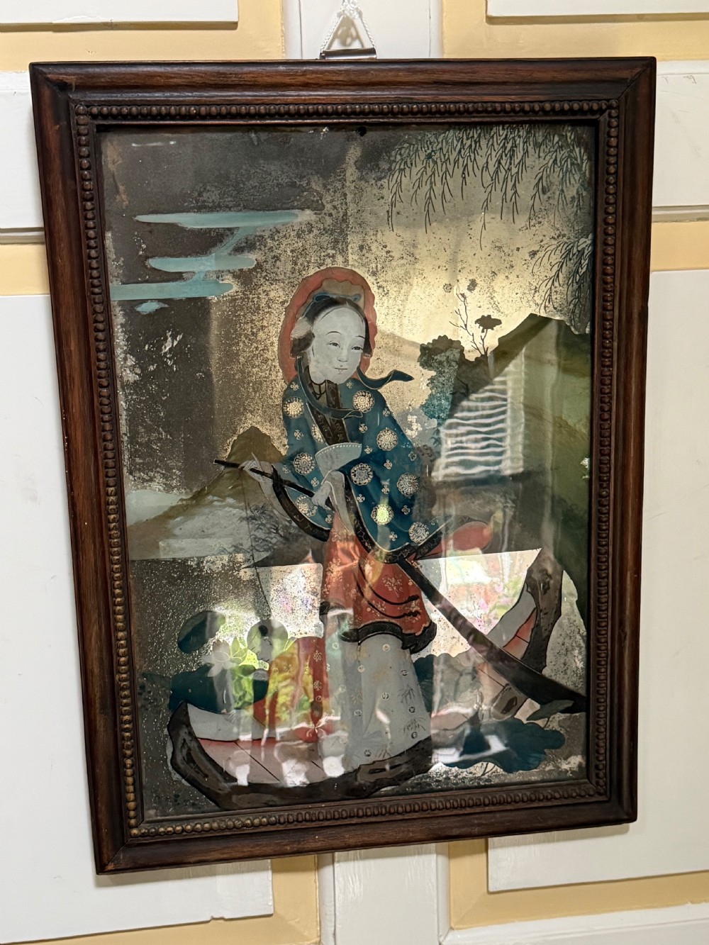 An early nineteenth-century Chinese export reverse glass picture featuring a figure on a boat against a silvered mirror background, encased in a dark wooden frame with beaded inner moulding. View III