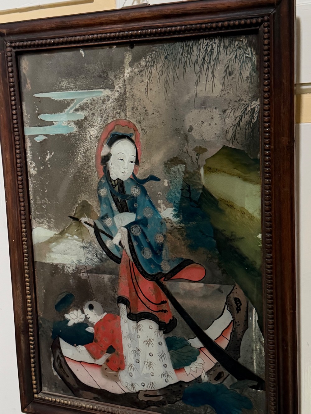 An early nineteenth-century Chinese export reverse glass picture featuring a figure on a boat against a silvered mirror background, encased in a dark wooden frame with beaded inner moulding. View VI