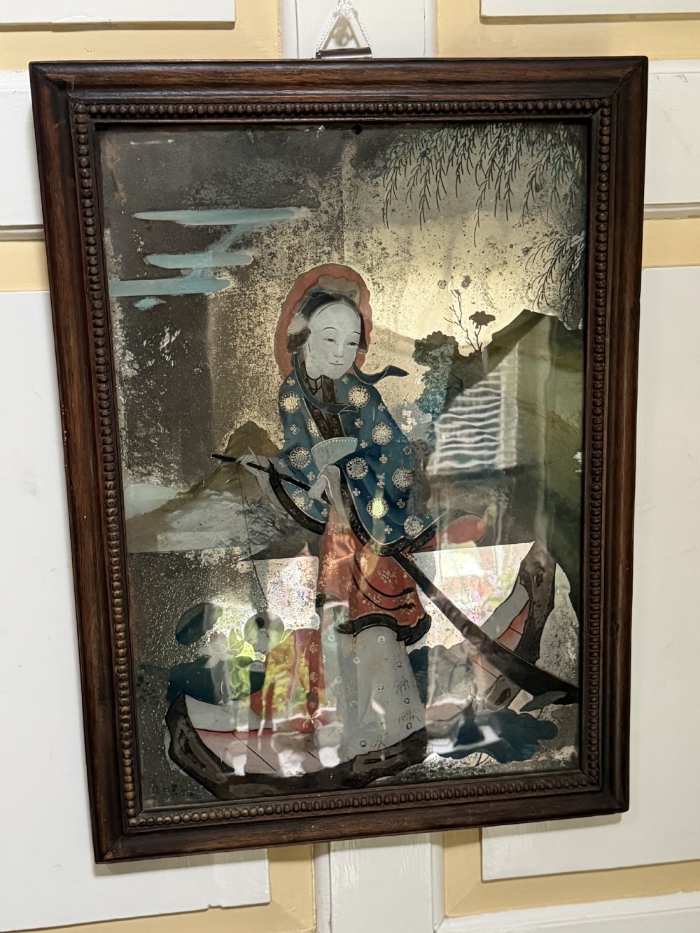 An early nineteenth-century Chinese export reverse glass picture featuring a figure on a boat against a silvered mirror background, encased in a dark wooden frame with beaded inner moulding. View XIII