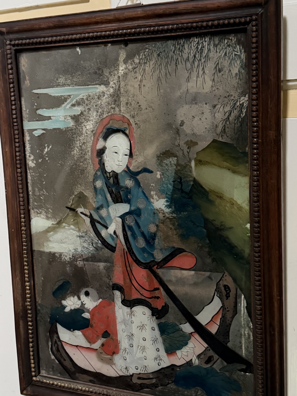 An early nineteenth-century Chinese export reverse glass picture featuring a figure on a boat against a silvered mirror background, encased in a dark wooden frame with beaded inner moulding. View XIV