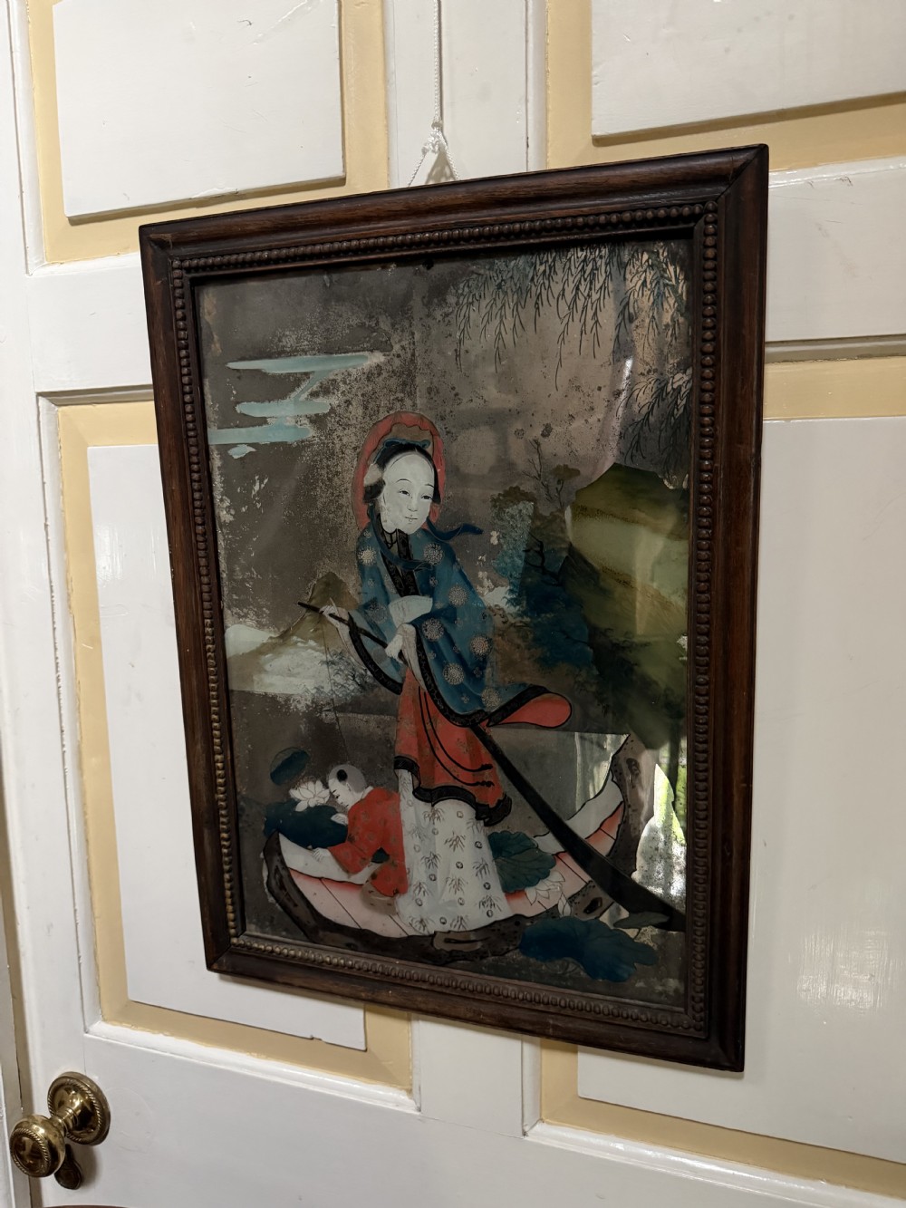 An early nineteenth-century Chinese export reverse glass picture featuring a figure on a boat against a silvered mirror background, encased in a dark wooden frame with beaded inner moulding. View XV
