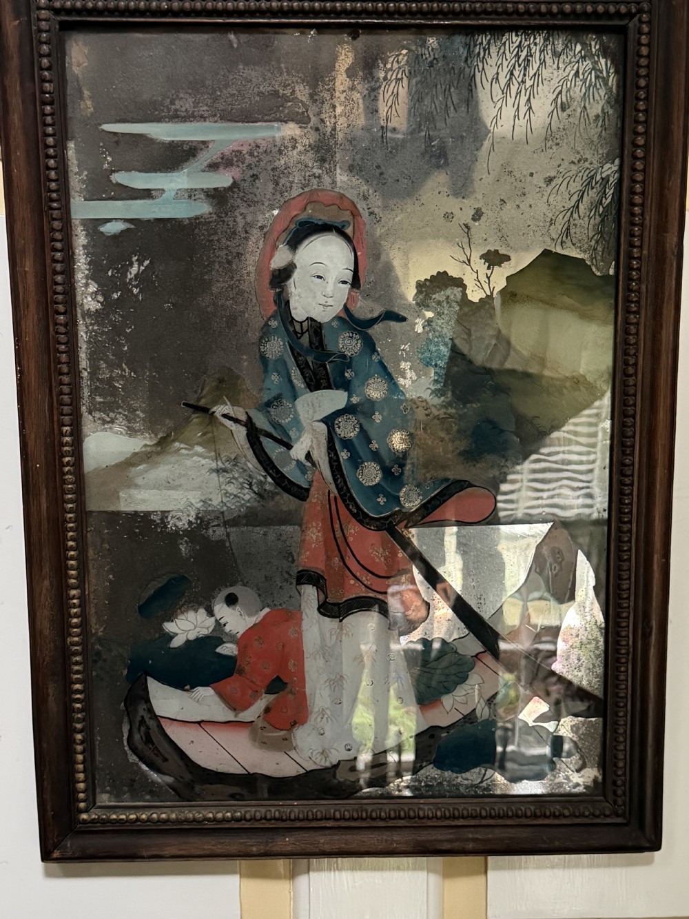 An early nineteenth-century Chinese export reverse glass picture featuring a figure on a boat against a silvered mirror background, encased in a dark wooden frame with beaded inner moulding. View XVI