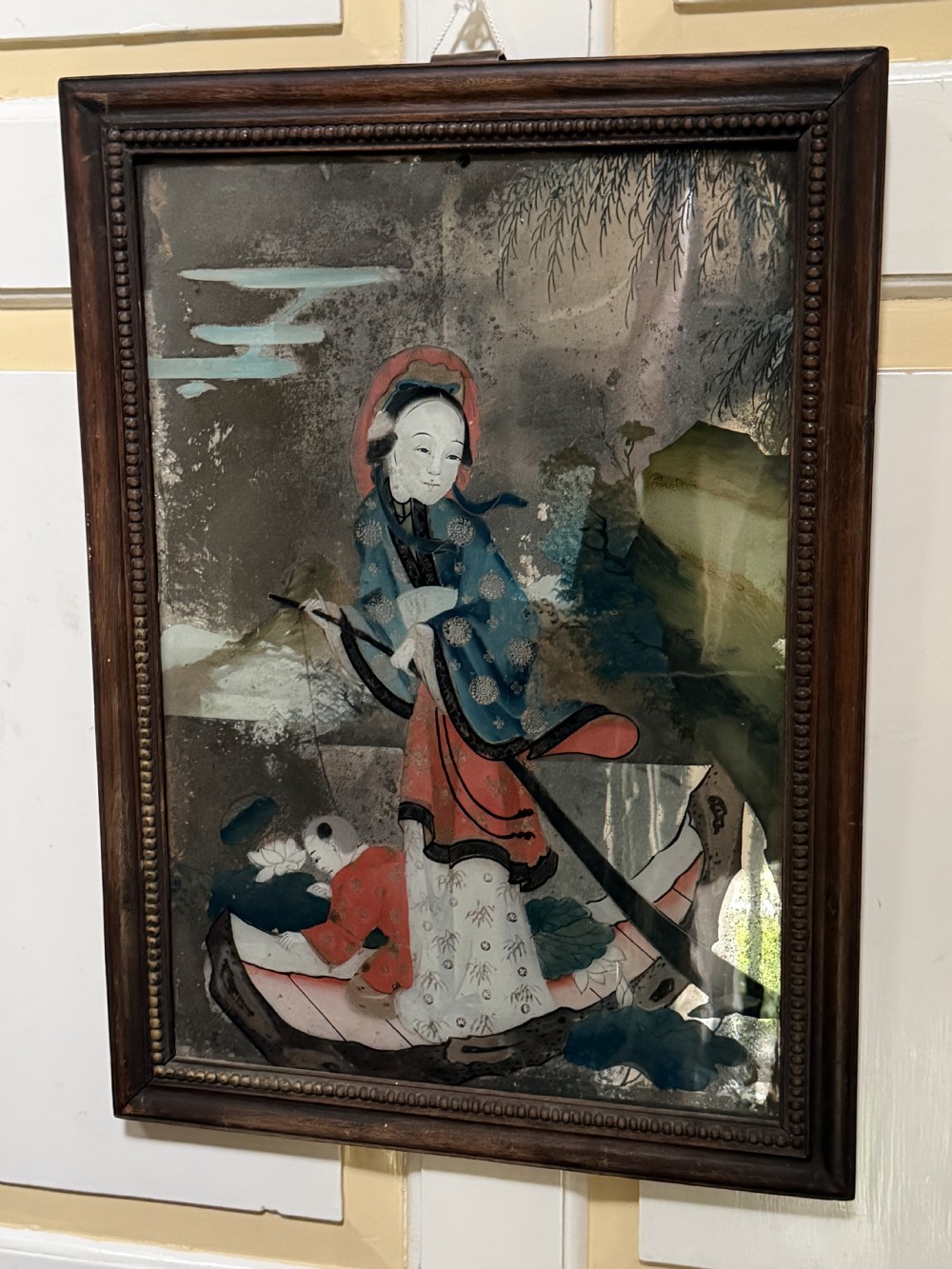 An early nineteenth-century Chinese export reverse glass picture featuring a figure on a boat against a silvered mirror background, encased in a dark wooden frame with beaded inner moulding. View XVII