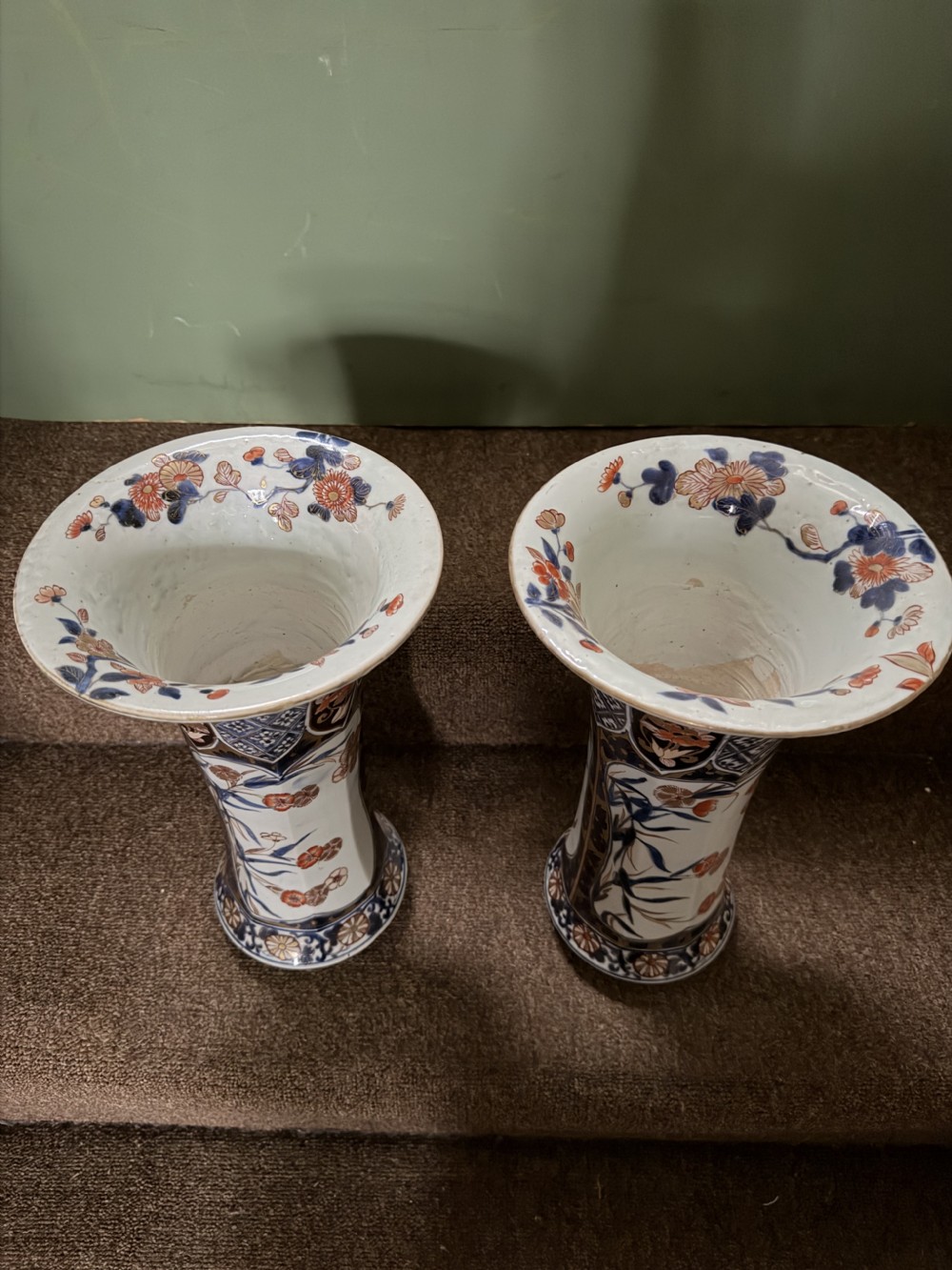 A three-piece Japanese Imari porcelain garniture featuring a central octagonal baluster jar flanked by two trumpet-shaped beaker vases, decorated with floral panels in cobalt blue, iron red, and gold. View VII