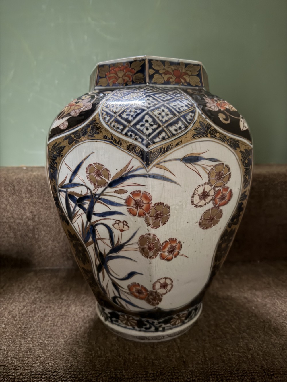 A three-piece Japanese Imari porcelain garniture featuring a central octagonal baluster jar flanked by two trumpet-shaped beaker vases, decorated with floral panels in cobalt blue, iron red, and gold. View VIII