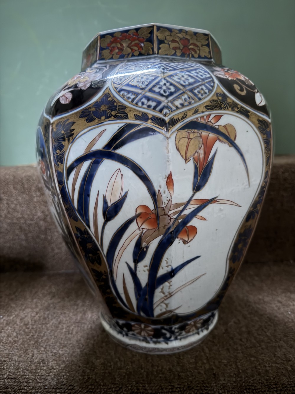 A three-piece Japanese Imari porcelain garniture featuring a central octagonal baluster jar flanked by two trumpet-shaped beaker vases, decorated with floral panels in cobalt blue, iron red, and gold. View XI