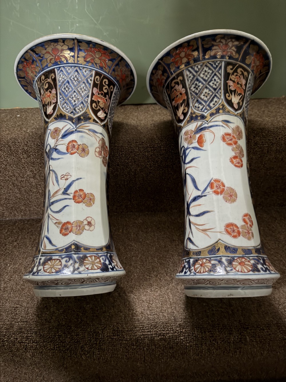 A three-piece Japanese Imari porcelain garniture featuring a central octagonal baluster jar flanked by two trumpet-shaped beaker vases, decorated with floral panels in cobalt blue, iron red, and gold. View XIII