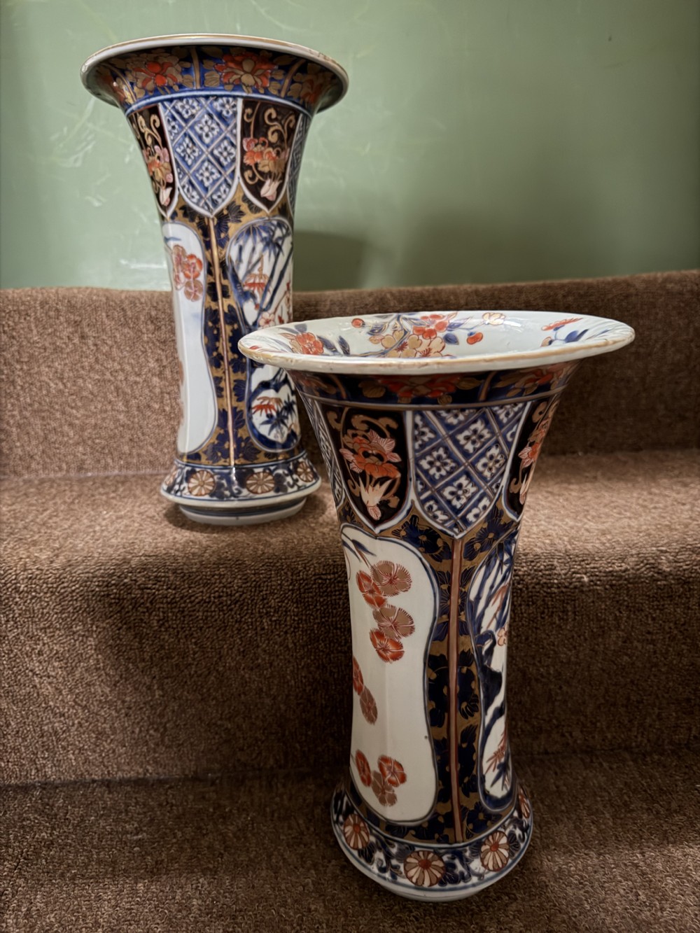 A three-piece Japanese Imari porcelain garniture featuring a central octagonal baluster jar flanked by two trumpet-shaped beaker vases, decorated with floral panels in cobalt blue, iron red, and gold. View XIV
