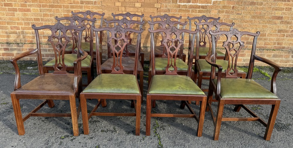 A set of twelve late nineteenth-century mahogany dining chairs featuring carved pierced back splats and green leather seats.