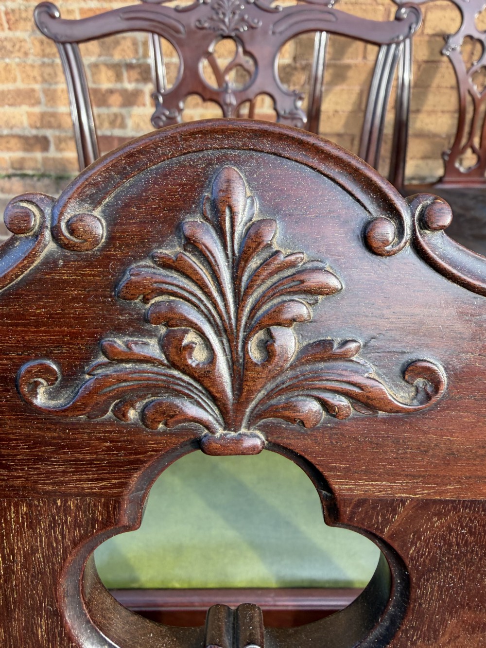 A set of twelve late nineteenth-century mahogany dining chairs featuring carved pierced back splats and green leather seats. View XVI