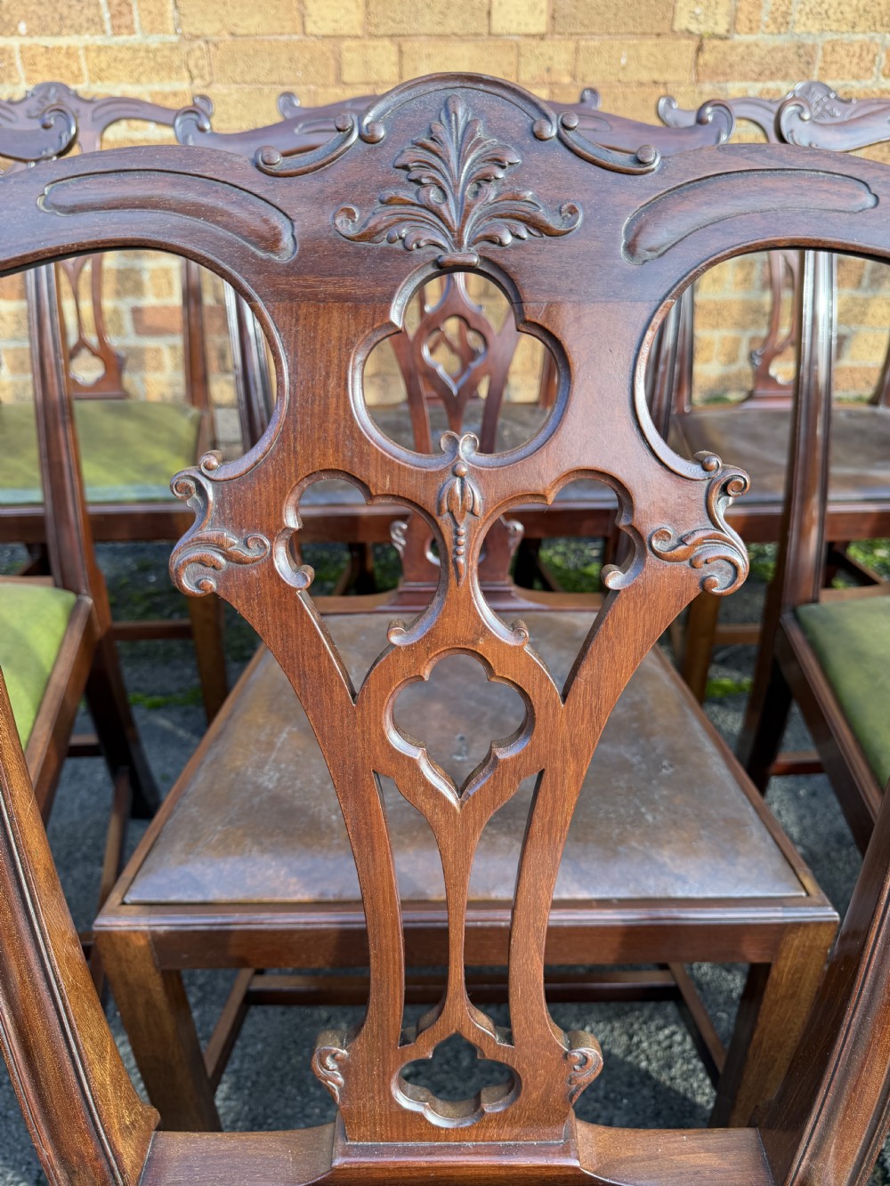 A set of twelve late nineteenth-century mahogany dining chairs featuring carved pierced back splats and green leather seats. View XVIII