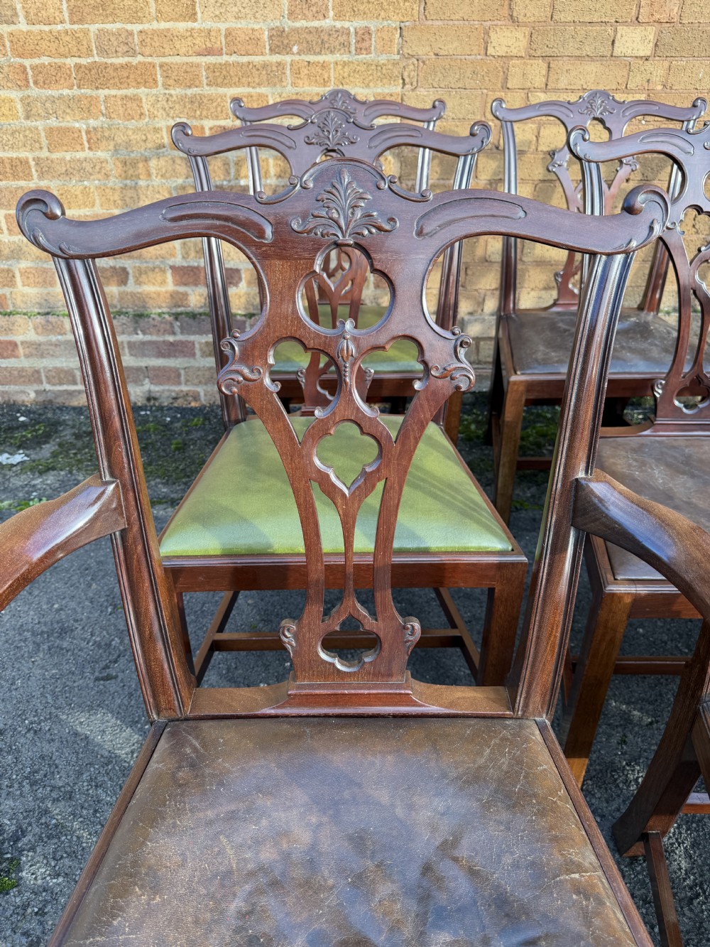 A set of twelve late nineteenth-century mahogany dining chairs featuring carved pierced back splats and green leather seats. View XIX