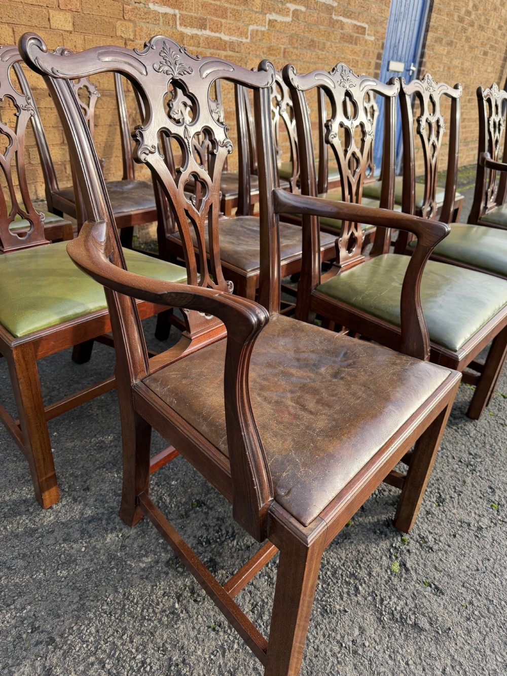 A set of twelve late nineteenth-century mahogany dining chairs featuring carved pierced back splats and green leather seats. View XXI
