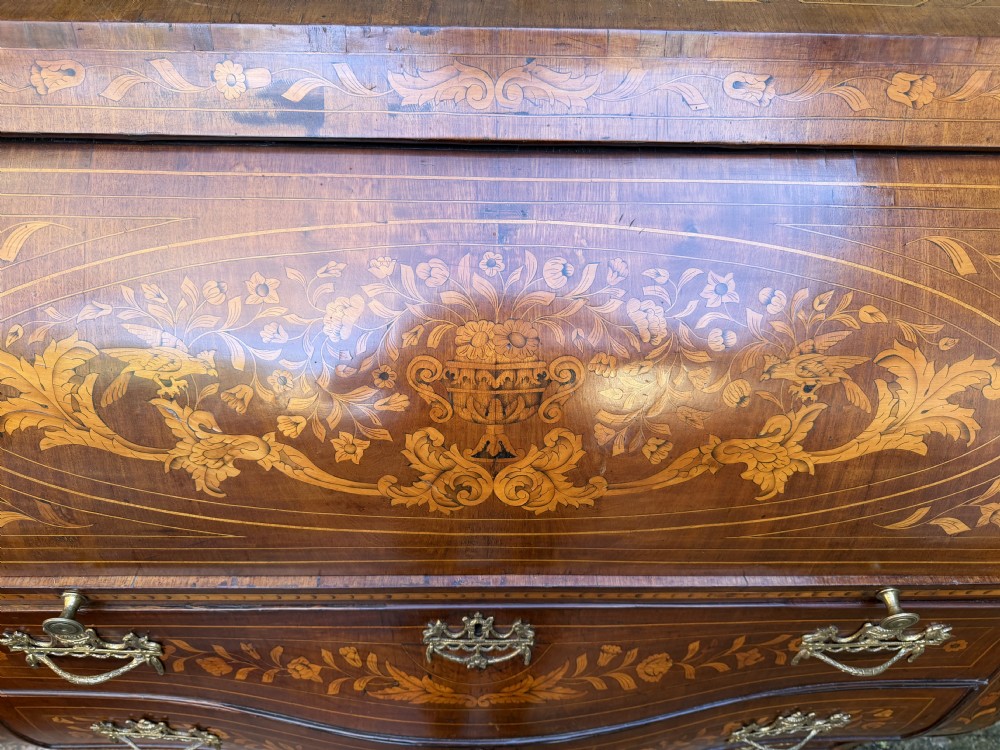 An antique Dutch walnut bureau with floral marquetry inlays, a curved cylinder front, three drawers, and decorative brass handles. View III