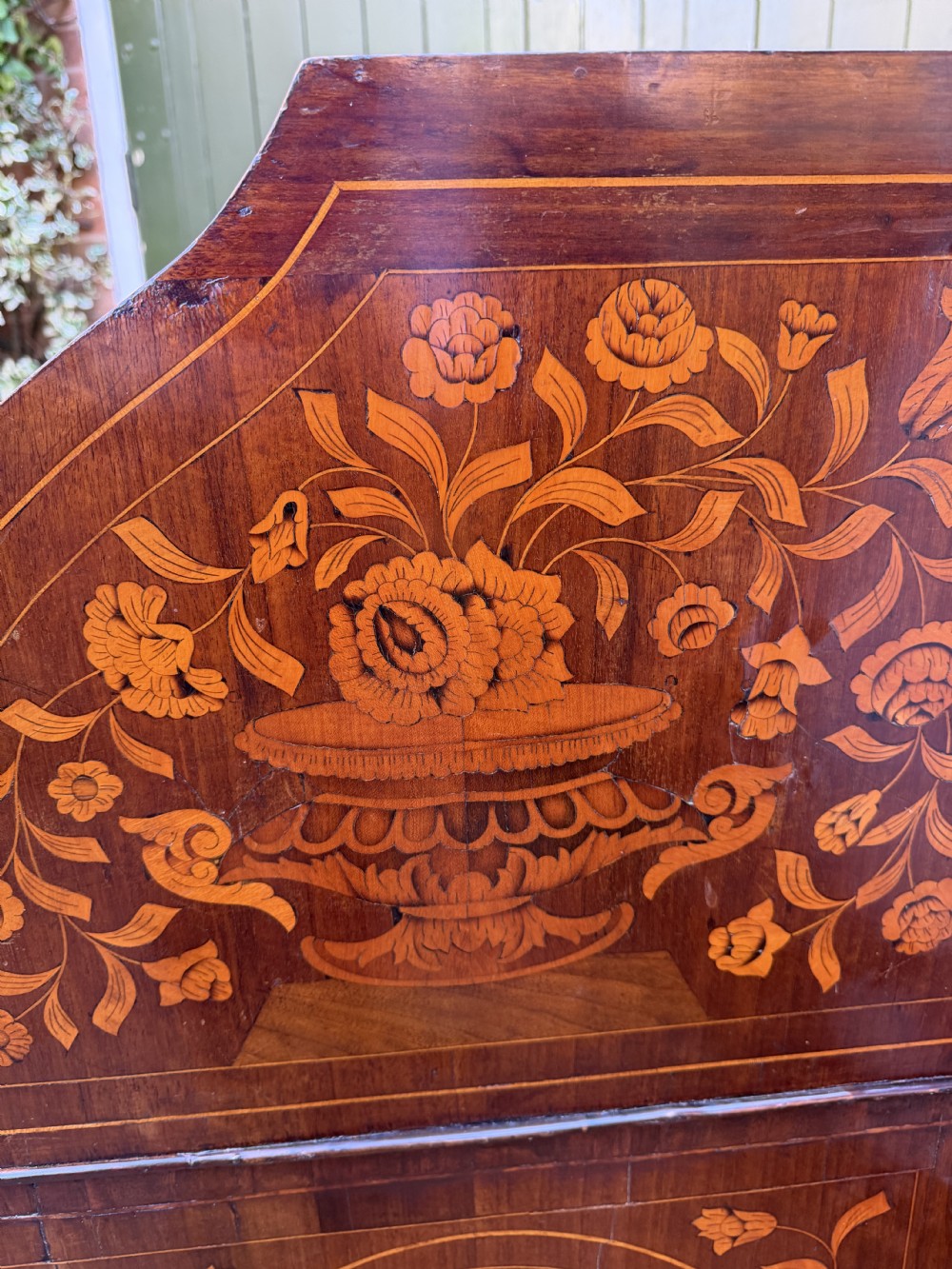 An antique Dutch walnut bureau with floral marquetry inlays, a curved cylinder front, three drawers, and decorative brass handles. View XII